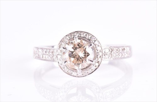 Lot 530 - A white and cognac diamond halo ring the...