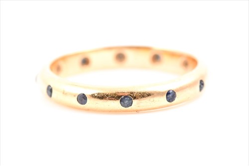 Lot 631 - A yellow metal and sapphire eternity ring...