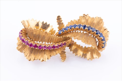 Lot 573 - A sapphire and ruby bow brooch in textured...