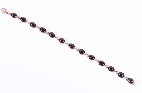 Lot 76 - A yellow metal and garnet bracelet set with...