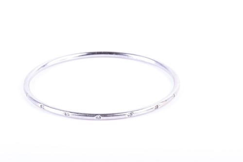 Lot 913 - An 18ct white gold and diamond bangle bracelet...