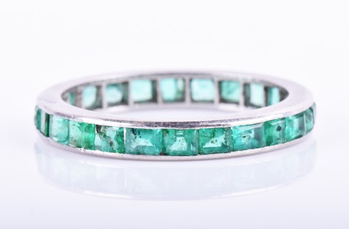 Lot 899 - An emerald eternity ring channel-set with...