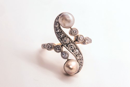Lot 740 - A diamond and pearl scroll ring, set with a...