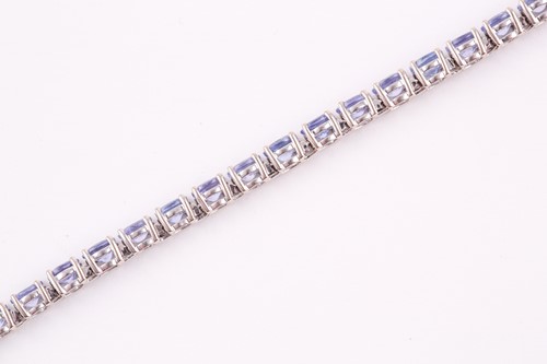 Lot 132 - An 18ct white gold and tanzanite line bracelet,...