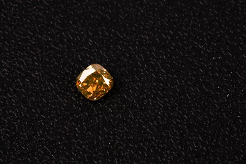 Lot 101 - A loose cushion-cut diamond, light orange,...