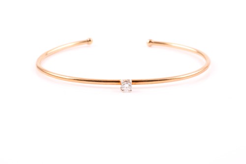 Lot 302 - A yellow metal and diamond bangle, set with a...