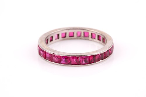 Lot 45 - A white metal and ruby eternity ring,...