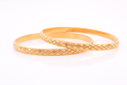 Lot 167 - A pair of Indian yellow metal bangles, with...