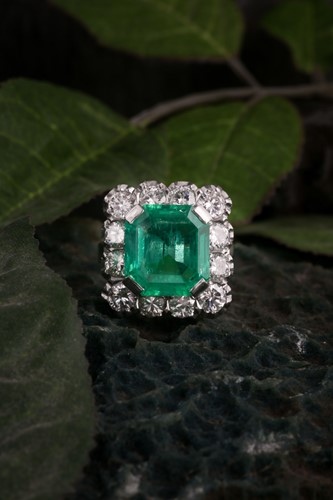 Lot 119 - An emerald and diamond cluster ring; the...