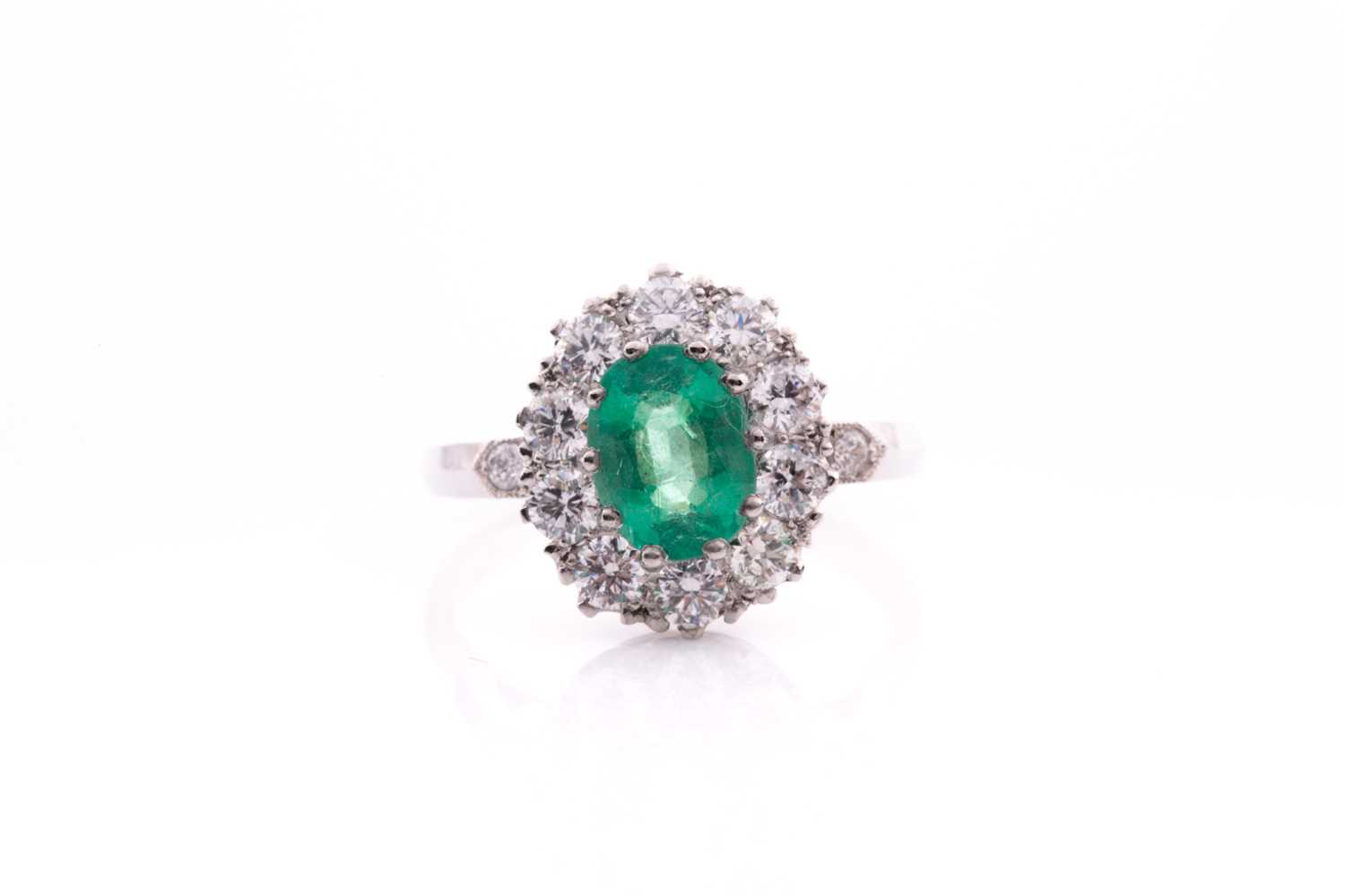 Lot 21 - A platinum, diamond, and emerald cluster ring,...