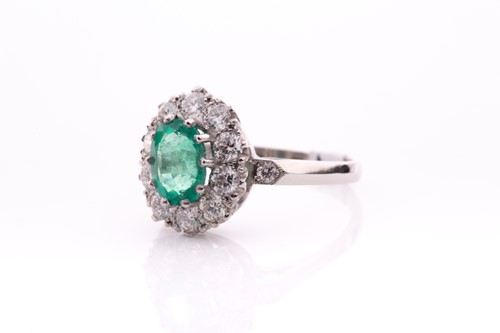 Lot 21 - A platinum, diamond, and emerald cluster ring,...