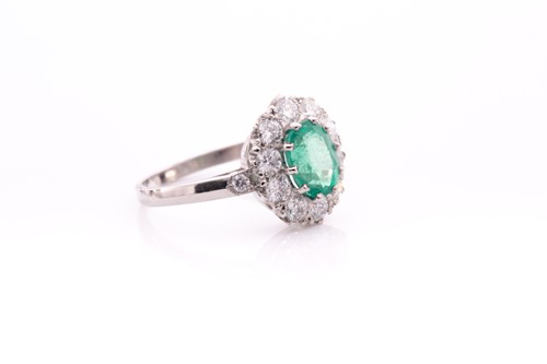 Lot 21 - A platinum, diamond, and emerald cluster ring,...