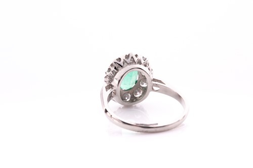 Lot 21 - A platinum, diamond, and emerald cluster ring,...