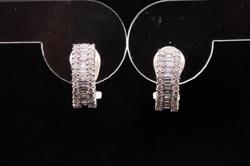 Lot 269 - A pair of white metal and diamond half hoop...