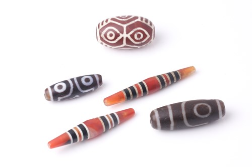 Lot 94 - A collection of five Tibetan carved agate Dzi...