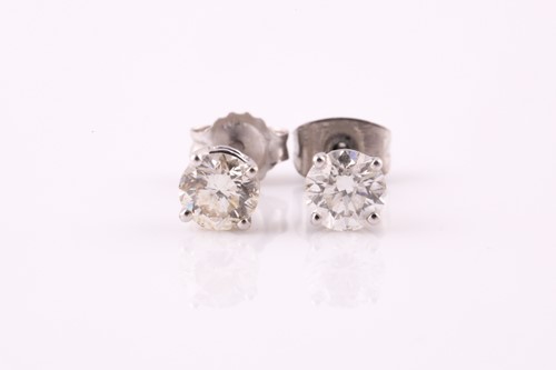 Lot 75 - A pair of single stone diamond earrings; the...