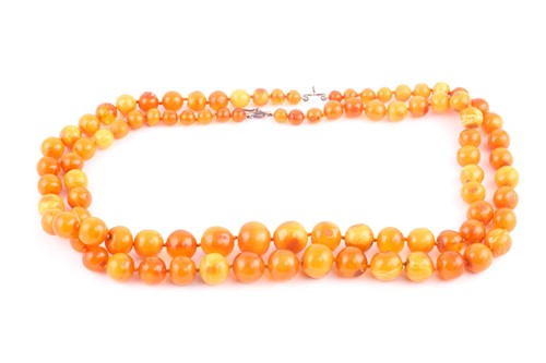 Lot 231 - A double-strand amber necklace, each...