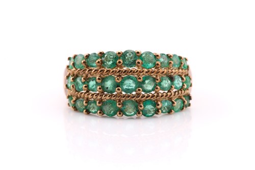 Lot 428 - A three-row emerald half hoop ring; the...