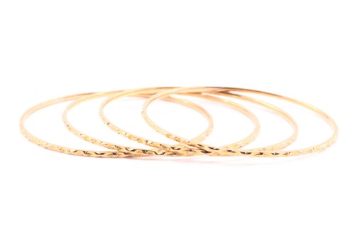 Lot 139 - A lot consisting of four yellow metal bangles...