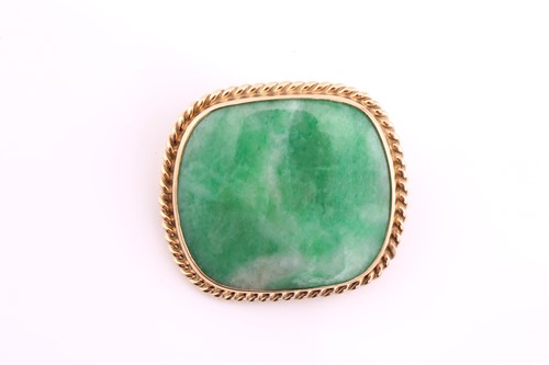 Lot 13 - A cushion shape jade cabochon brooch, within a...