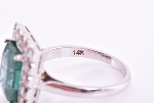 Lot 46 - An emerald and diamond halo ring, consisting...