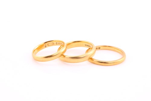 Lot 398 - Three gold wedding bands, each hallmarked 22ct,...