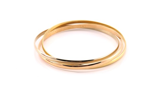 Lot 33 - A Cartier trinity bracelet, featuring three...