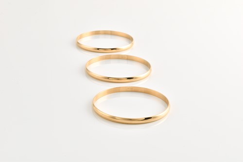 Lot 181 - Three solid closed bangles in yellow metal,...