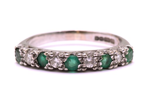 Lot 204 - An Emerald and diamond half eternity ring in...