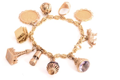 Lot 117 - A rope chain bracelet with assorted charms,...
