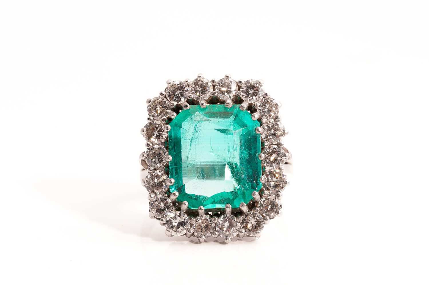 Lot 21 - An emerald and diamond entourage ring,...