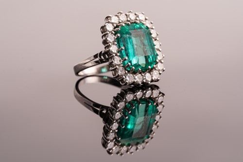 Lot 21 - An emerald and diamond entourage ring,...