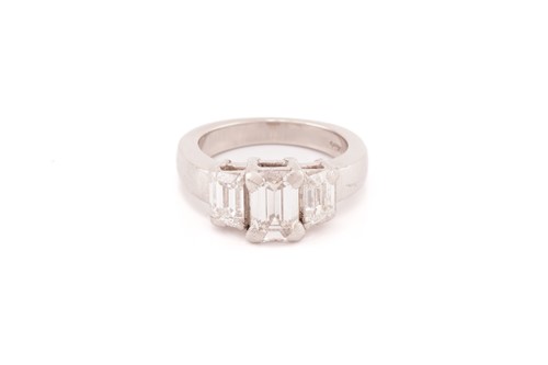 Lot 190 - An emerald-cut diamond trilogy ring in...