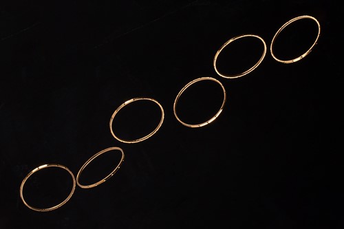 Lot 222 - A suite of six yellow metal bangles, with a...