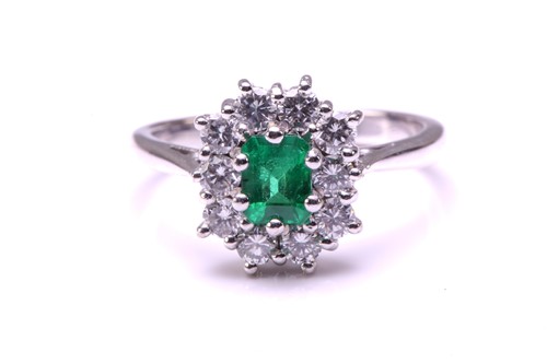 Lot 11 - An emerald and diamond entourage ring in 18ct...
