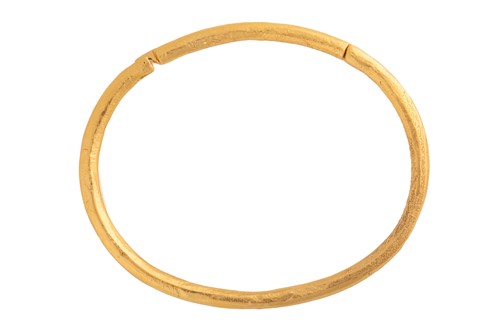 Lot 280 - A hinged bangle with tension clasp, textured...