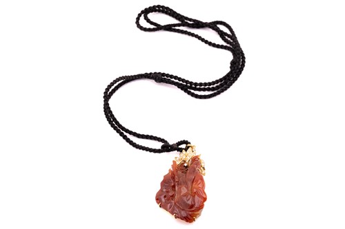 Lot 206 - A carved red jadeite and diamond pendant on a...