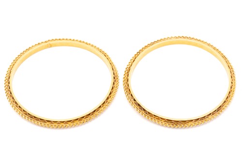 Lot 77 - A pair of high-carat gold closed bangles, with...