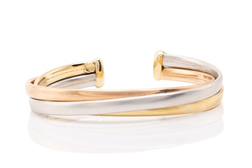 Lot 91 - A tri-coloured torque bracelet consisting of...