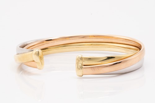 Lot 91 - A tri-coloured torque bracelet consisting of...