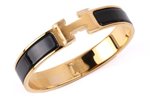 Lot 140 - Hermès - A narrow 'Clic H' bracelet with black...