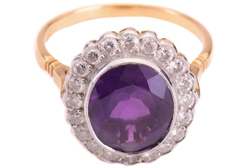 Lot 50 - An amethyst and diamond halo ring, featuring...