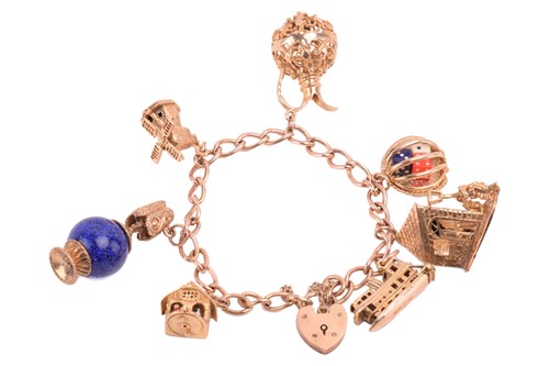 Lot 259 - A curb link charm bracelet in 9ct gold,...