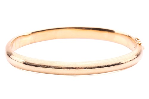 Lot 145 - A yellow metal bangle; brushed finish, with a...