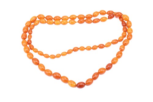 Lot 24 - A butterscotch oval amber bead necklace,...