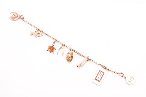 Lot 147 - A charm bracelet with various charms,...