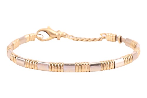 Lot 122 - An 18 carat gold bi-coloured bangle; the inner...