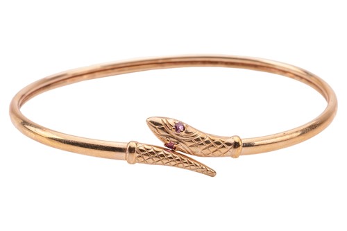 Lot 29 - A ruby-set snake bangle in 9ct gold, featuring...