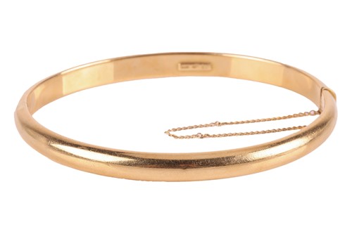 Lot 89 - A hollow hinged bangle in 18ct yellow gold,...