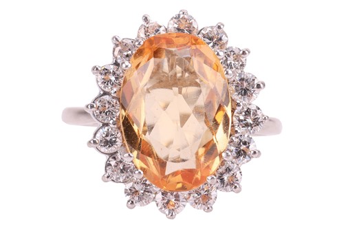 Lot 19 - A topaz and diamond halo ring, centred with an...